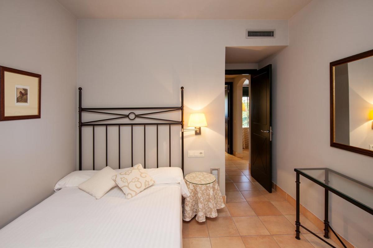 Un dormitorio con una cama blanca y un pasillo. en Apartahotel Suites Vila Birdie, en Navata 28 fotos más