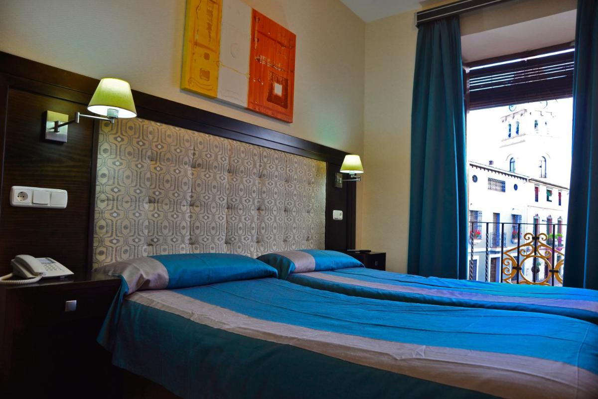 Un dormitorio con una cama con sábanas azules y una ventana. en Hotel & Spa PLAZA Arriate, en Arriate 76 fotos más