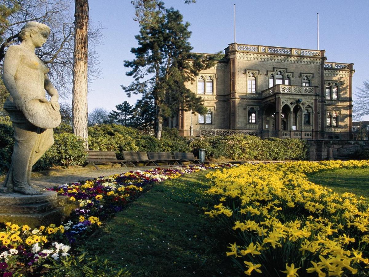 eine Statue vor einem Gebäude mit Blumen in der Unterkunft Colombi Hotel in Freiburg im Breisgau