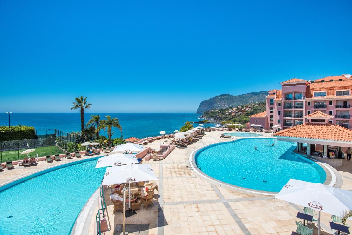 uma piscina com guarda-sóis e o oceano ao fundo em Pestana Royal All Inclusive Ocean & Spa Resort no Funchal