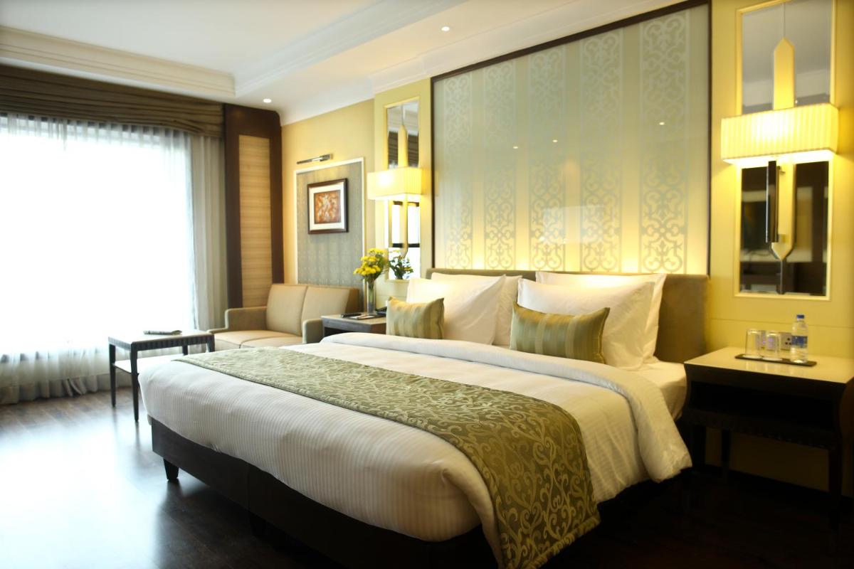 a hotel room with a large bed and a couch at Ramada Plaza Chennai in Chennai