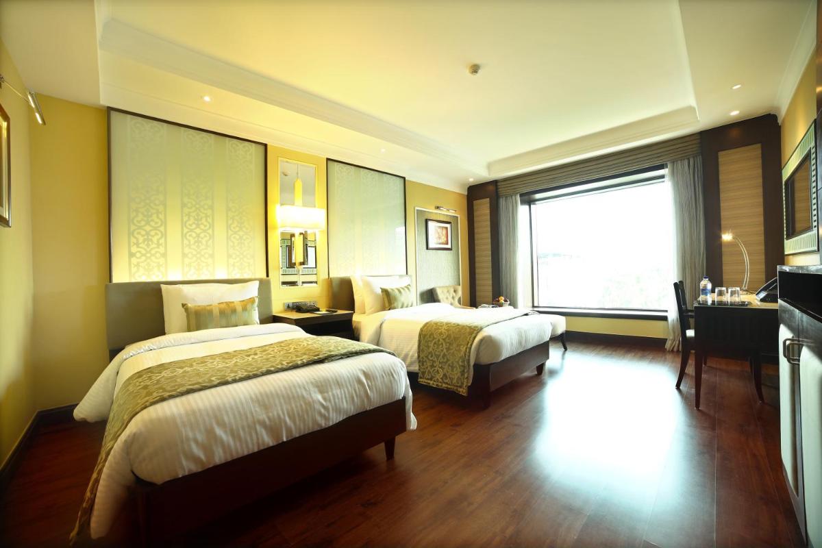a hotel room with two beds and a window at Ramada Plaza Chennai in Chennai