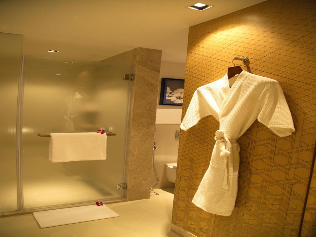 a bathroom with a shower and a white robe at Welcomhotel by ITC Hotels, RaceCourse, Coimbatore in Coimbatore