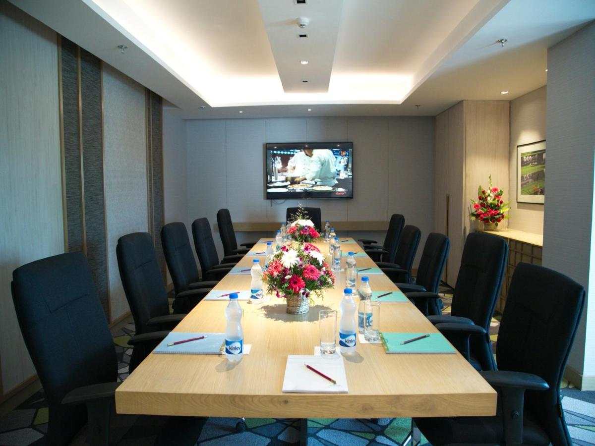 a large conference room with a long table with flowers at Welcomhotel by ITC Hotels, RaceCourse, Coimbatore in Coimbatore