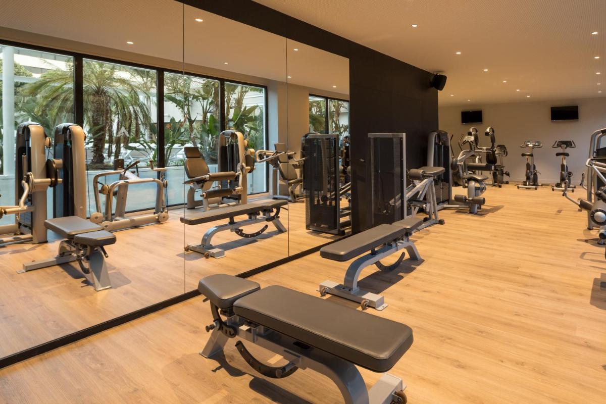 Un gimnasio con una fila de máquinas de correr y espejos. en AQUA Hotel Silhouette & Spa - Adults Only, en Malgrat de Mar