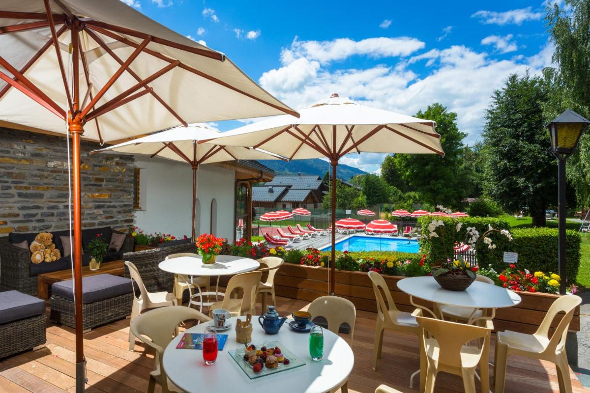 une terrasse avec tables et parasols et une piscine dans l'établissement Chalet-Hôtel Neige et Roc, The Originals Relais, à Samoëns