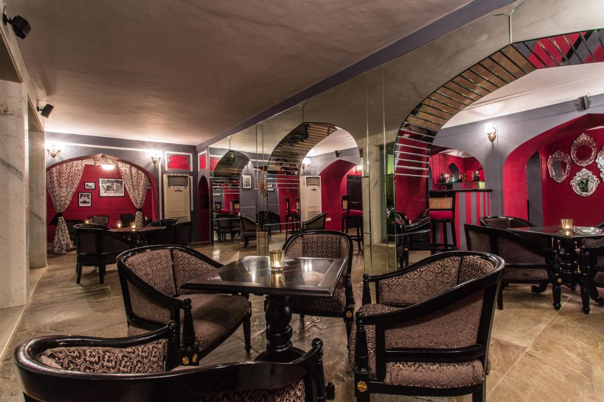 a restaurant with tables and chairs and red walls at Royal Heritage Haveli - By Leisure Hotels in Jaipur