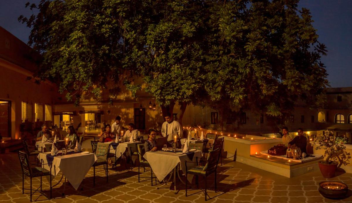 a group of people sitting at tables in a courtyard at night at Royal Heritage Haveli - By Leisure Hotels in Jaipur