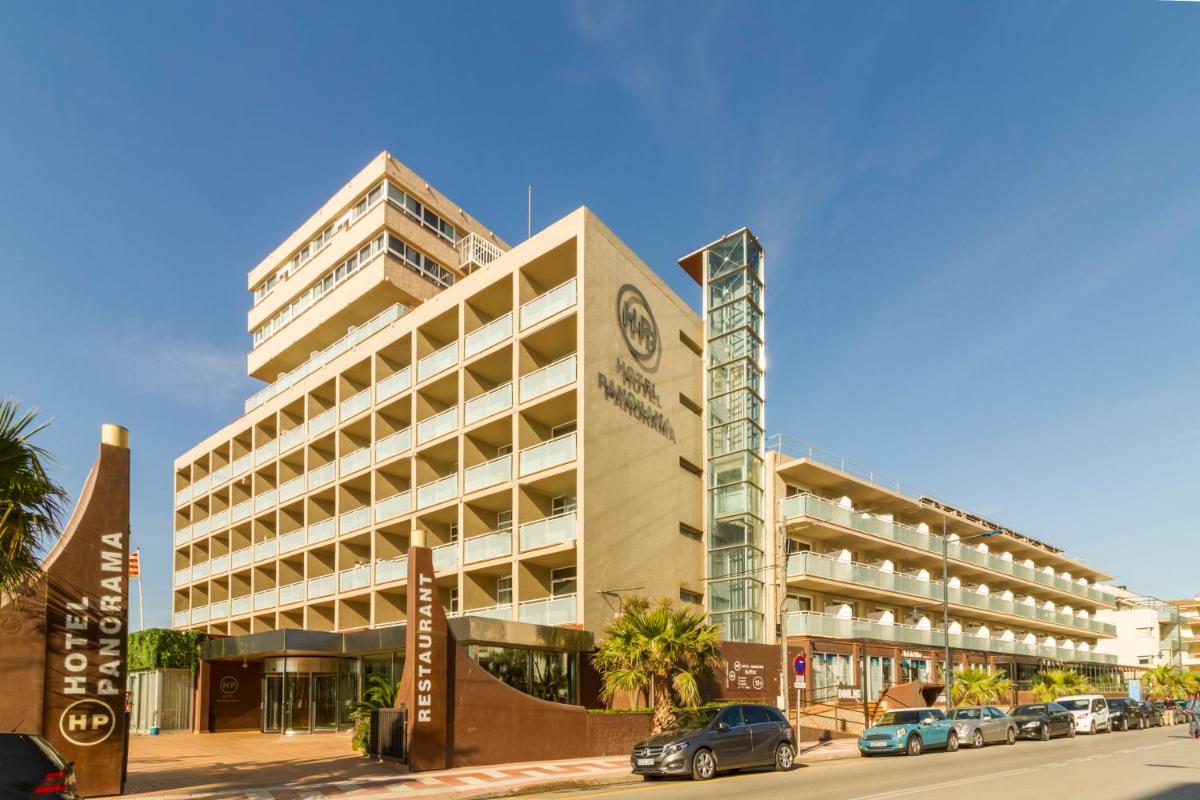 Un gran edificio con coches aparcados delante. en Hotel Panorama, en L'Estartit