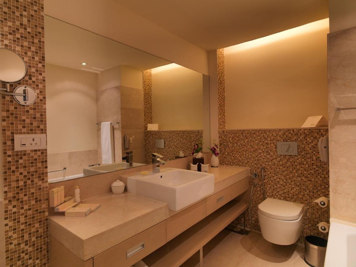 a bathroom with a sink and a toilet and a mirror at Radisson Blu Hotel, Greater Noida in Greater Noida