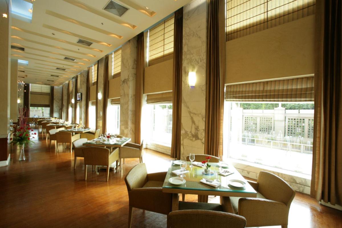 a dining room with tables and chairs and windows at Jaypee Vasant Continental in New Delhi