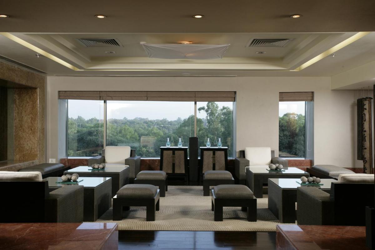 a waiting room with tables and chairs and a large window at Jaypee Vasant Continental in New Delhi