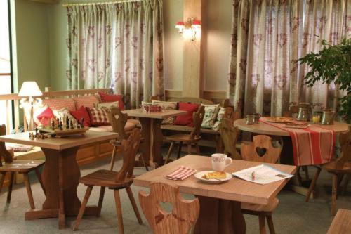 - une salle à manger avec des tables, des chaises et des rideaux dans l'établissement Hôtel Restaurant La Tourmaline, à Aime La Plagne