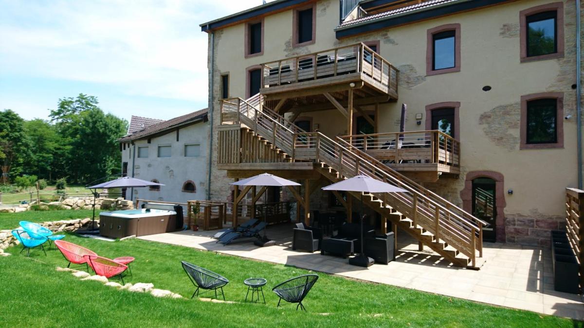une maison avec une terrasse et des chaises dans le jardin dans l'établissement Le Moulin d'Oscar & Spa - Mulhouse Nord, à Baldersheim