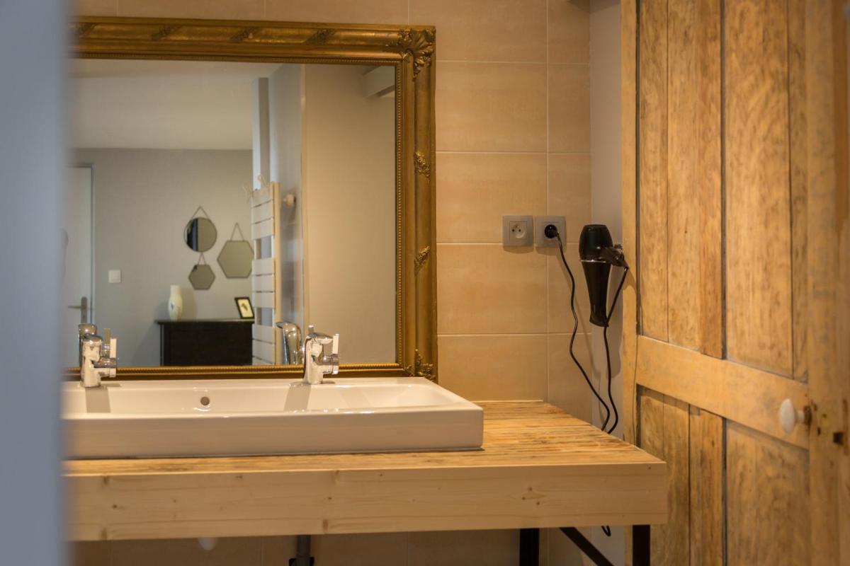une salle de bains avec un lavabo et un miroir dans l'établissement Le Miel des Muses, à Brive-la-Gaillarde 19 autres photos