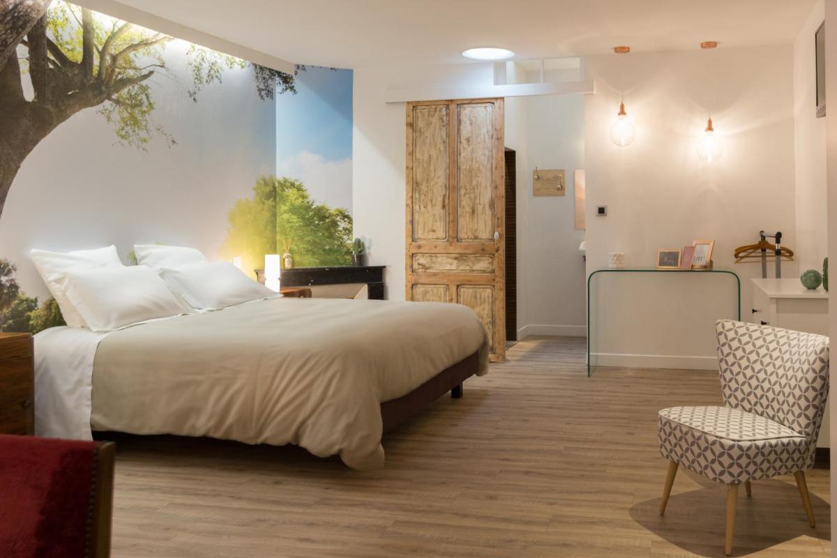 une chambre avec un lit, une chaise et une porte dans l'établissement Le Miel des Muses, à Brive-la-Gaillarde