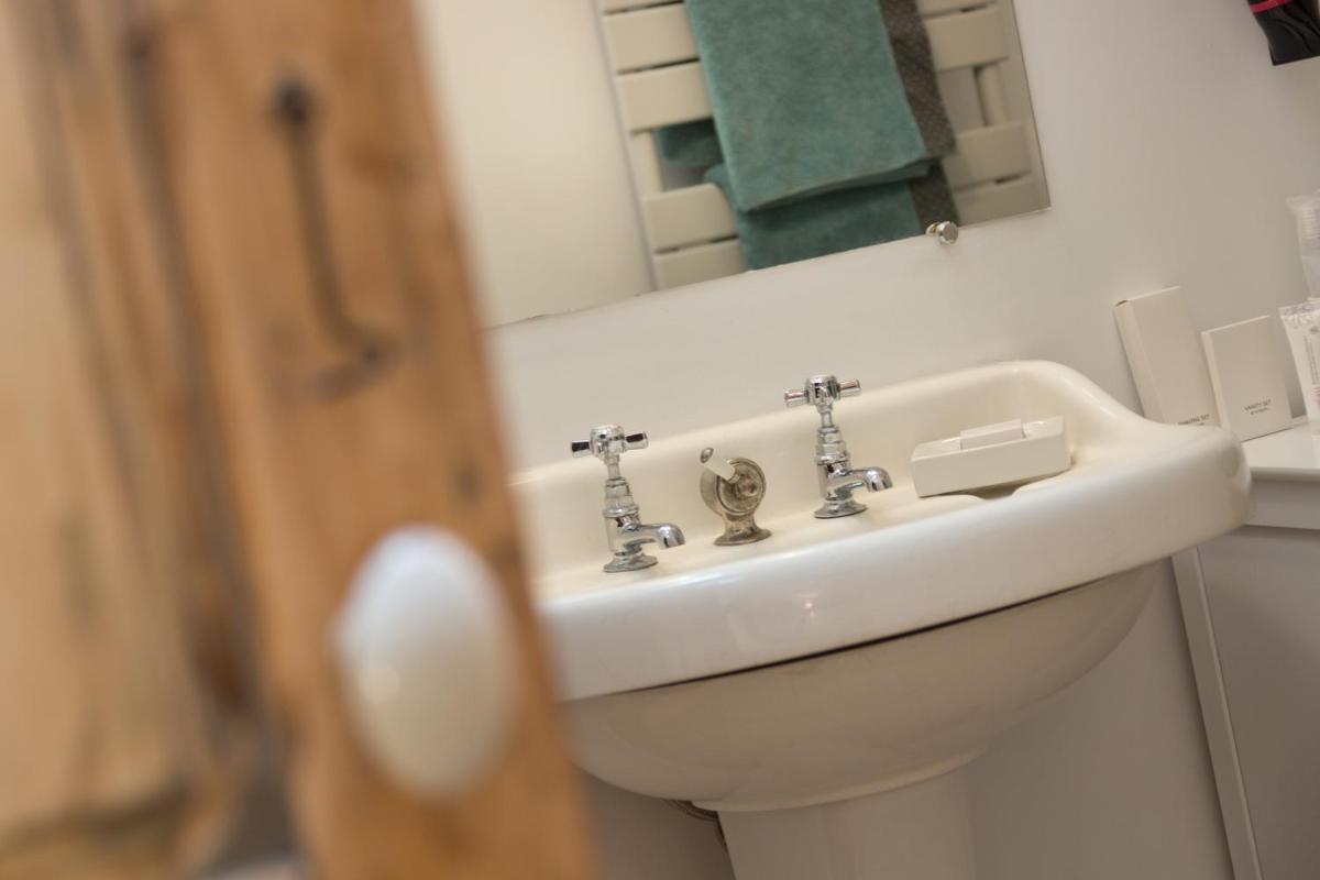 une salle de bains avec un lavabo blanc et un miroir dans l'établissement Le Miel des Muses, à Brive-la-Gaillarde