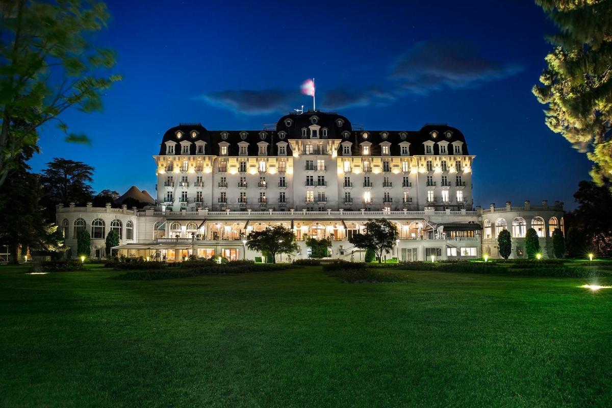 un grand bâtiment avec un drapeau au sommet la nuit dans l'établissement Impérial Palace, à Annecy