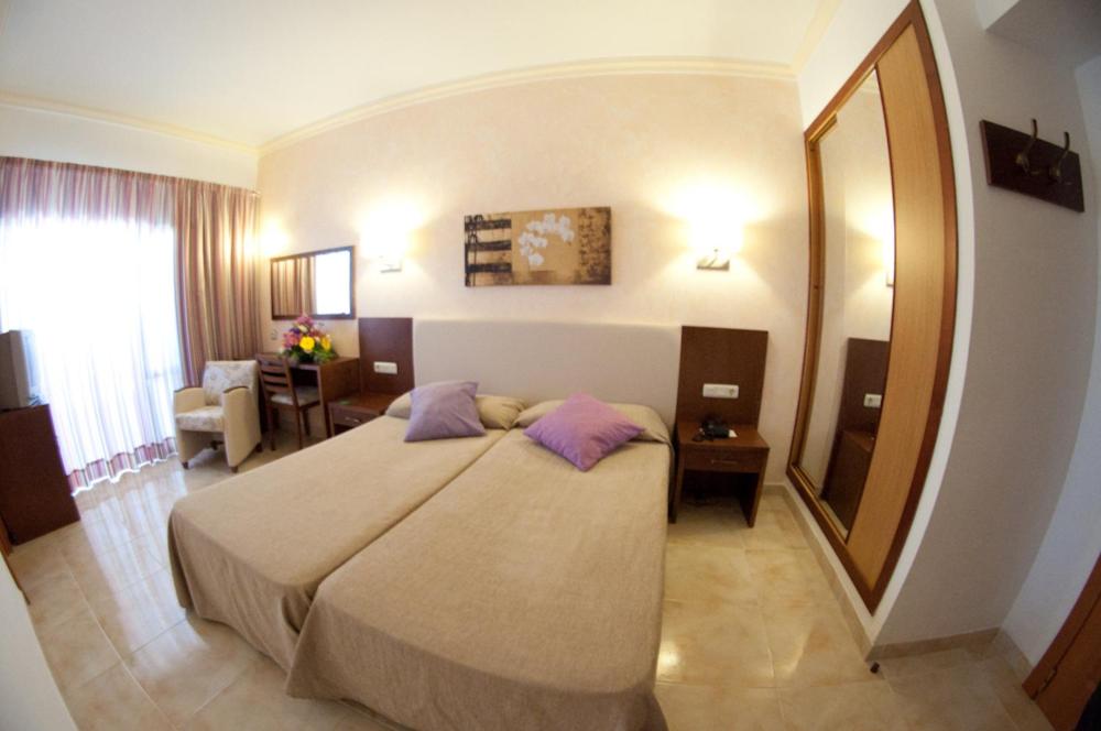 Un dormitorio con una cama grande y un espejo grande. en Hotel Cala Gat, en Cala Ratjada