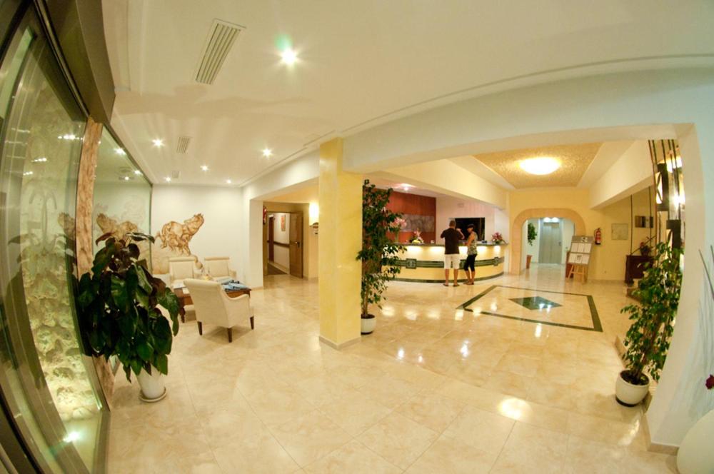 Una gran sala con un vestíbulo con plantas. en Hotel Cala Gat, en Cala Ratjada