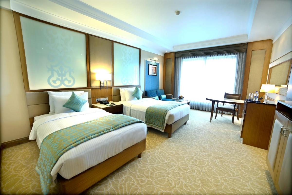 a hotel room with two beds and a desk at Ramada Plaza Chennai in Chennai