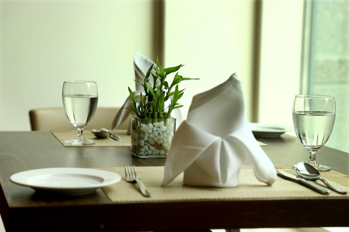 a table with a plate and wine glasses on it at Ramada Plaza Chennai in Chennai