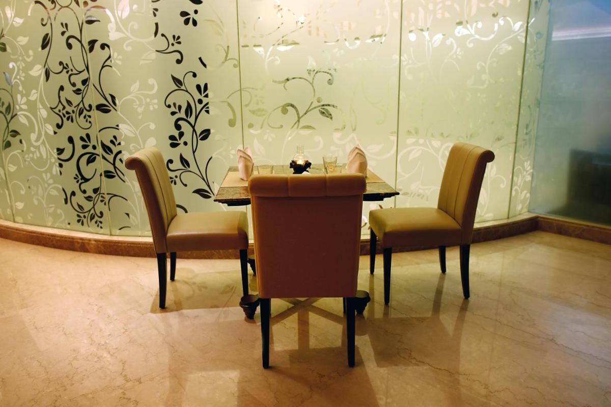 a table and chairs in a room with a wall at Ramada Plaza Chennai in Chennai