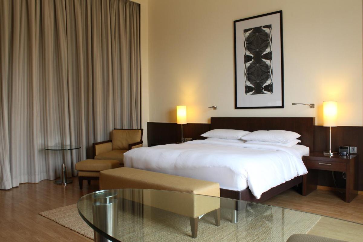 a hotel room with a bed and a glass table at Hyatt Hyderabad Gachibowli in Hyderabad