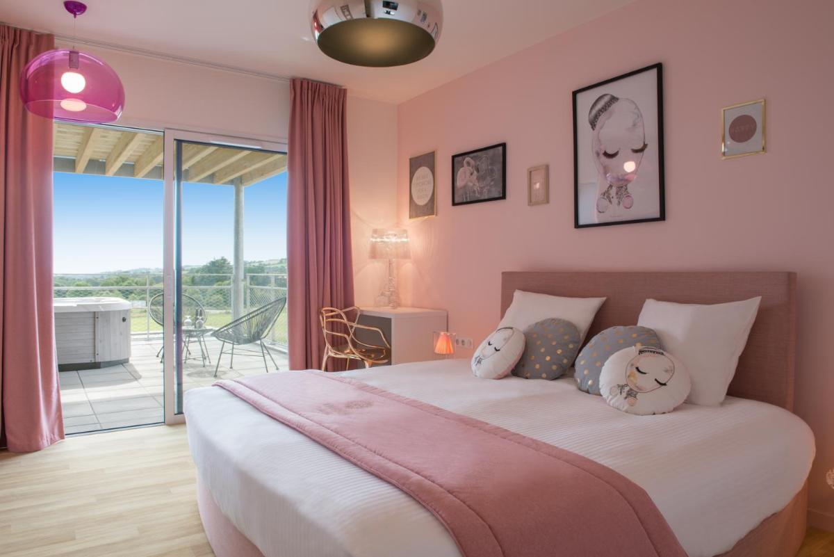 - une chambre avec un lit aux murs roses et un balcon dans l'établissement Hôtel Omnubo Collection, aux Épesses