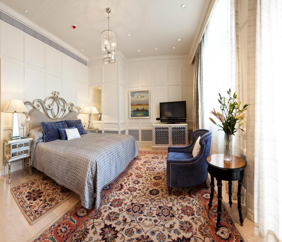 a bedroom with a bed and a chair and a television at The Taj Mahal Palace, Mumbai in Mumbai +36 photos a bedroom with a bed and a chair and a television at The Taj Mahal Palace, Mumbai in Mumbai +36 photos