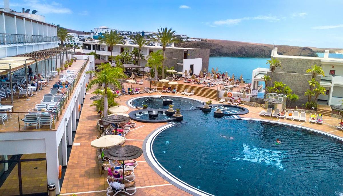 una piscina en un hotel con gente sentada a su alrededor en Hotel Mirador Papagayo by LIVVO, en Playa Blanca