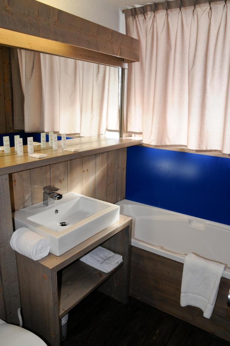 une salle de bain avec un lavabo et une baignoire dans l'établissement Hôtel Arcadien, à Arc 1600