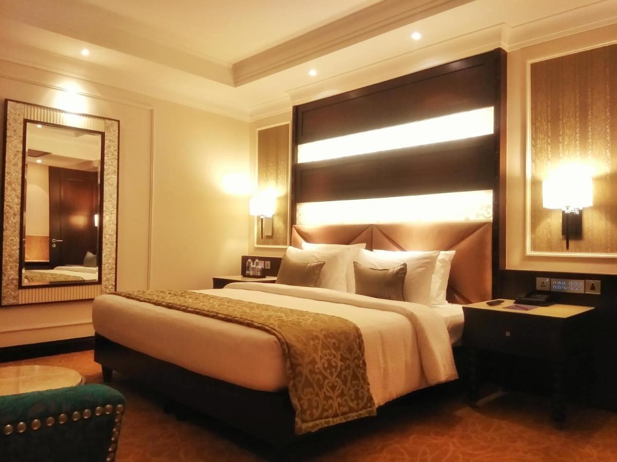 a bedroom with a large bed and a large mirror at Ramada Plaza Chennai in Chennai