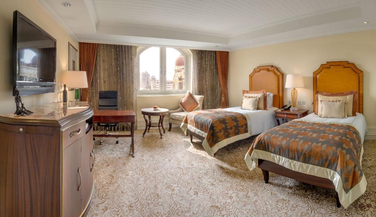 a hotel room with two beds and a television at The Taj Mahal Palace, Mumbai in Mumbai a hotel room with two beds and a television at The Taj Mahal Palace, Mumbai in Mumbai