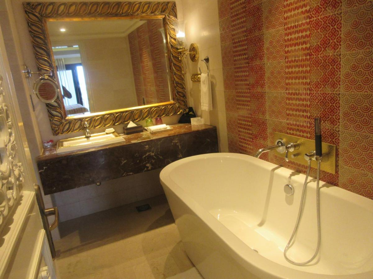 a bathroom with a tub and a sink and a mirror at Fragrant Nature Kochi - A Five star Classified Hotel in Cochin
