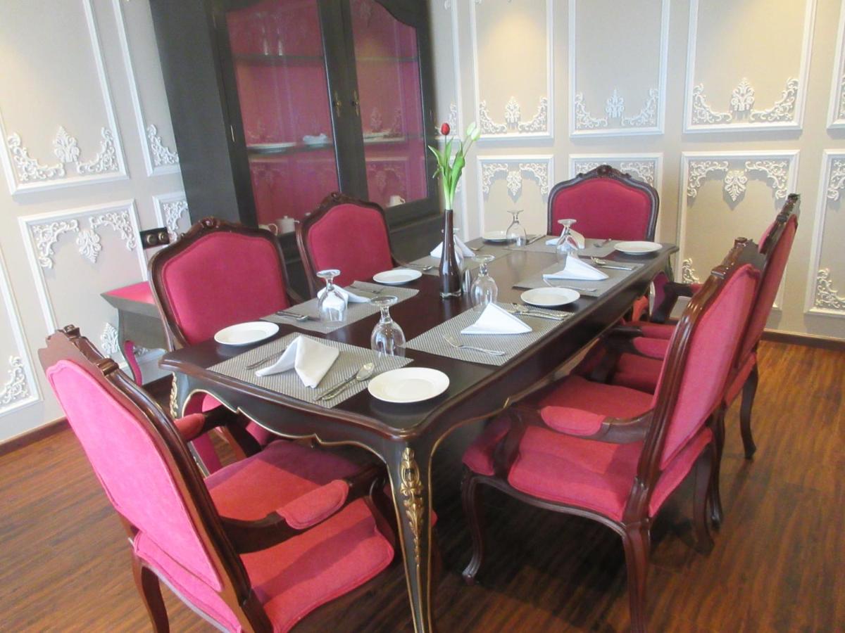 a dining room table with pink chairs around it at Fragrant Nature Kochi - A Five star Classified Hotel in Cochin