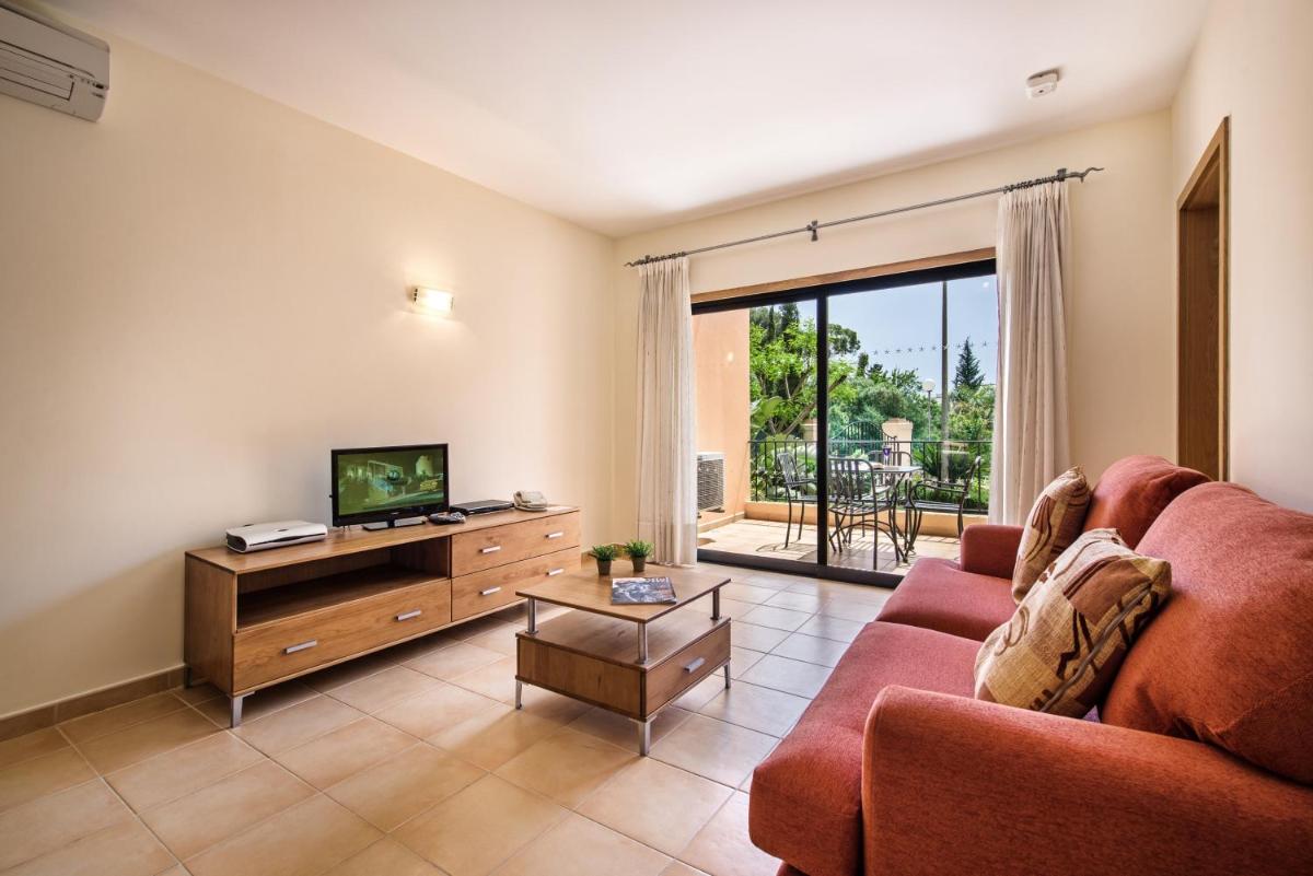 uma sala de estar com um sofá e uma TV em Estrela da Luz Resort na Praia da Luz