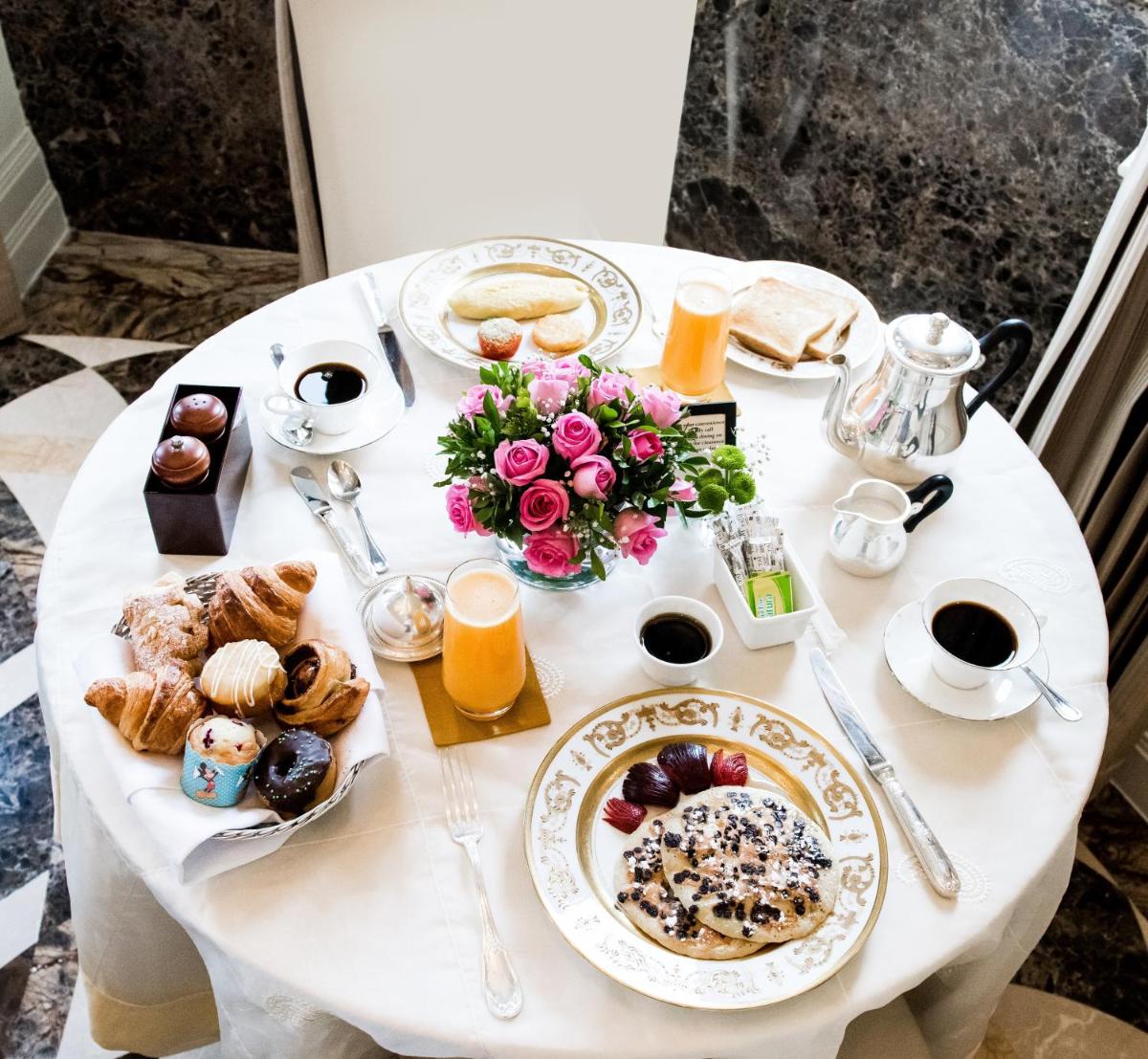 a white table with breakfast foods and orange juice at The Taj Mahal Palace, Mumbai in Mumbai a white table with breakfast foods and orange juice at The Taj Mahal Palace, Mumbai in Mumbai