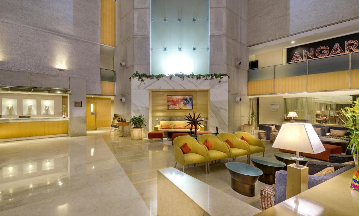 a lobby of a hotel with yellow chairs and tables at Pride Plaza Hotel, Ahmedabad in Ahmedabad
