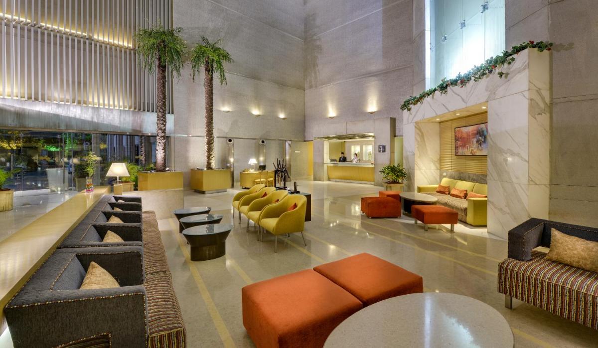 a lobby with couches and chairs in a building at Pride Plaza Hotel, Ahmedabad in Ahmedabad