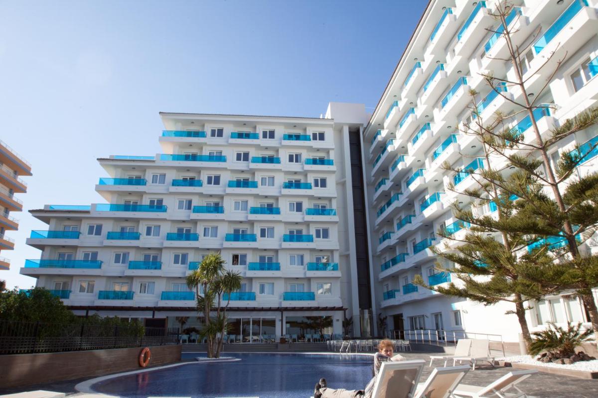 Un gran edificio con una piscina en frente. en Aparthotel Acuazul, en Peñíscola