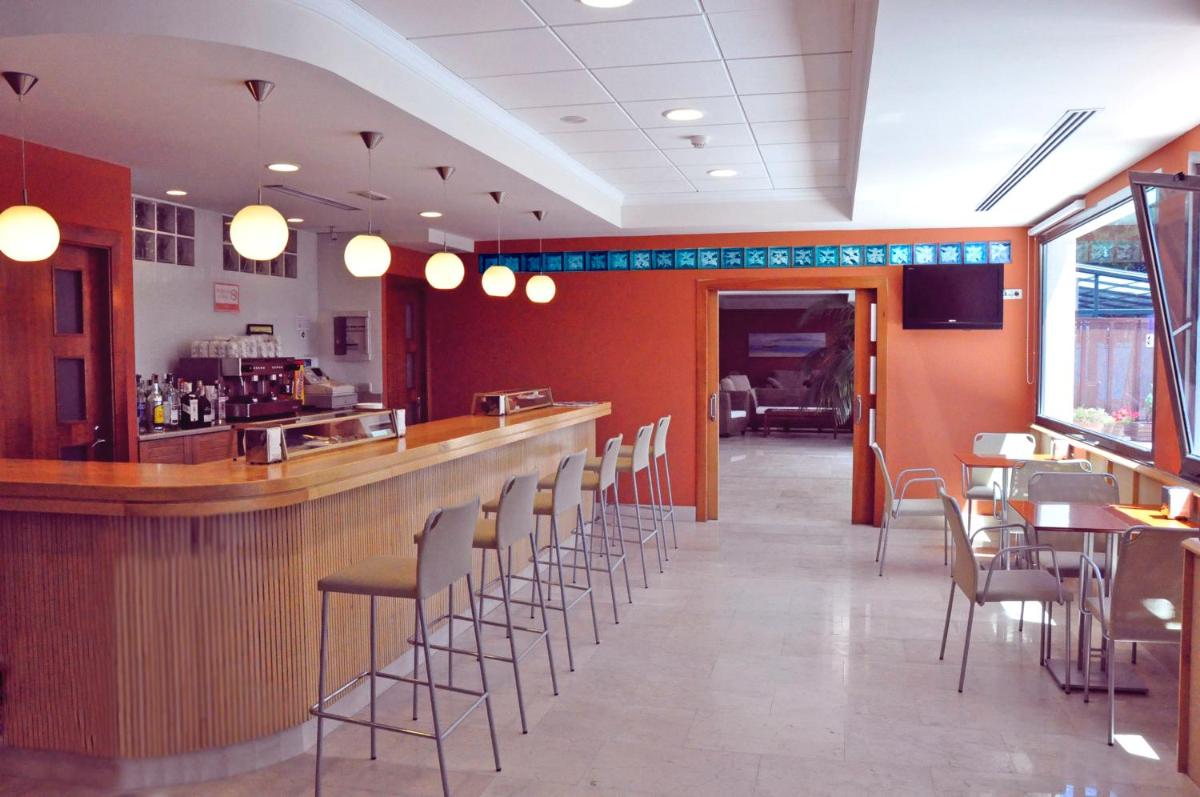 un restaurante con un bar con sillas y mesas en Hotel San Millán, en Santander