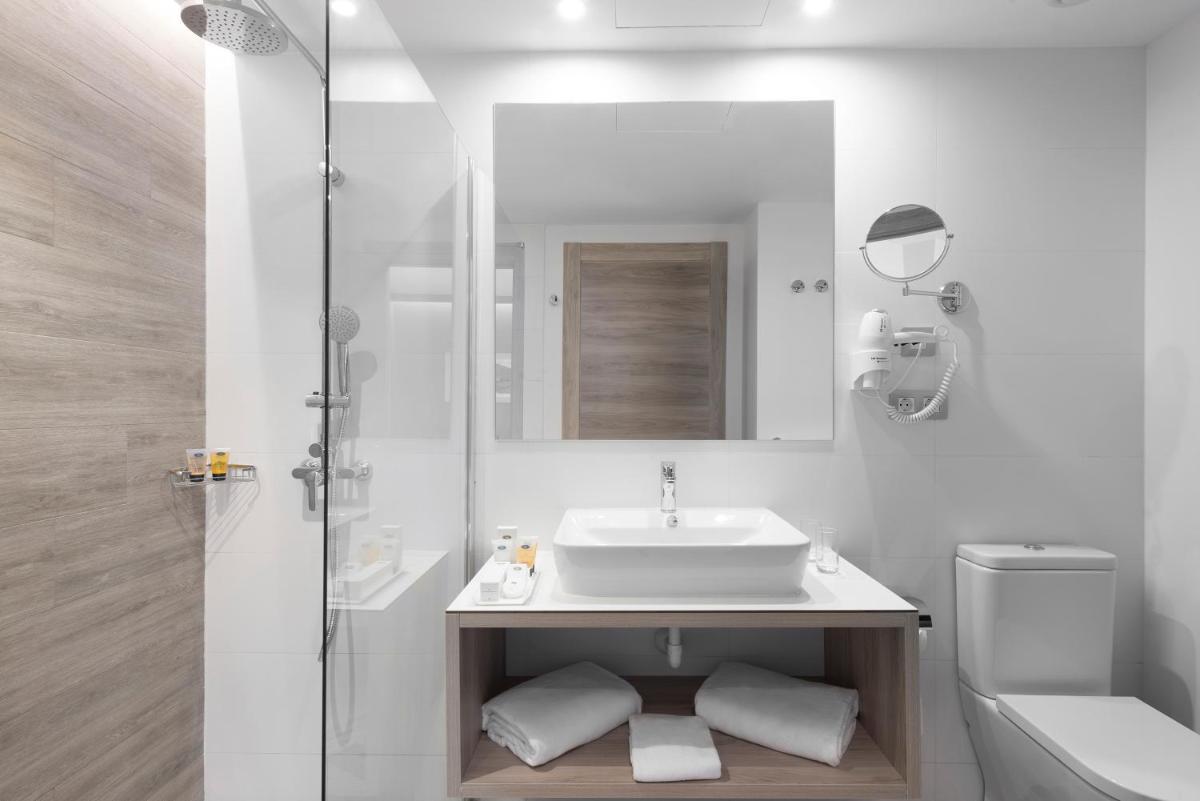 Un baño blanco con lavabo y espejo. en Elba Lanzarote Royal Village Resort, en Playa Blanca