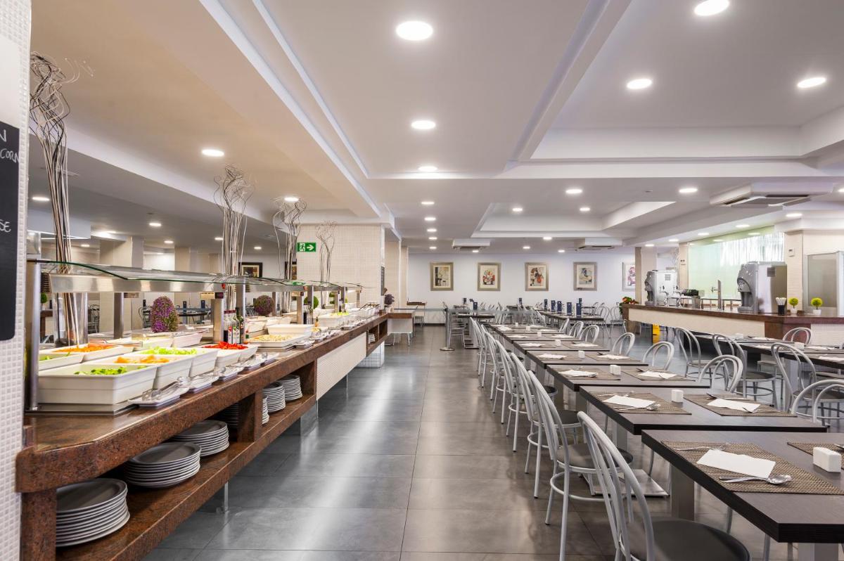 Un comedor con mesas largas y sillas. en Kn Aparthotel Columbus, en Playa de las Américas