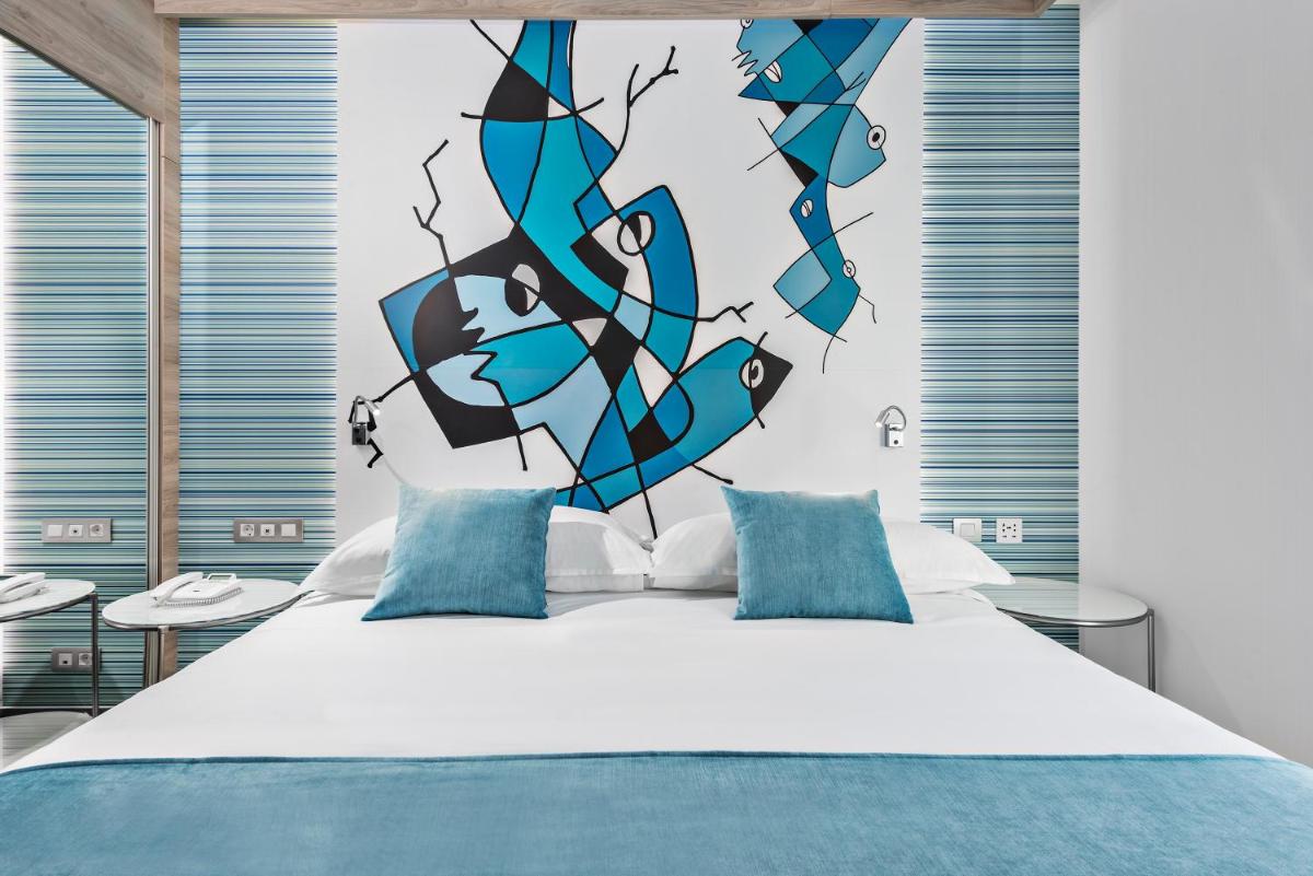 1 dormitorio con 1 cama con pared azul y negra en Elba Lanzarote Royal Village Resort, en Playa Blanca
