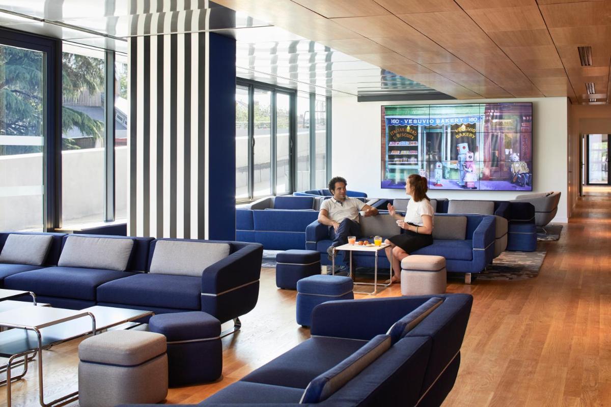2 personnes assises sur des canapés bleus dans une salle d'attente dans l'établissement YOOMA Urban Lodge Tour Eiffel, à Paris