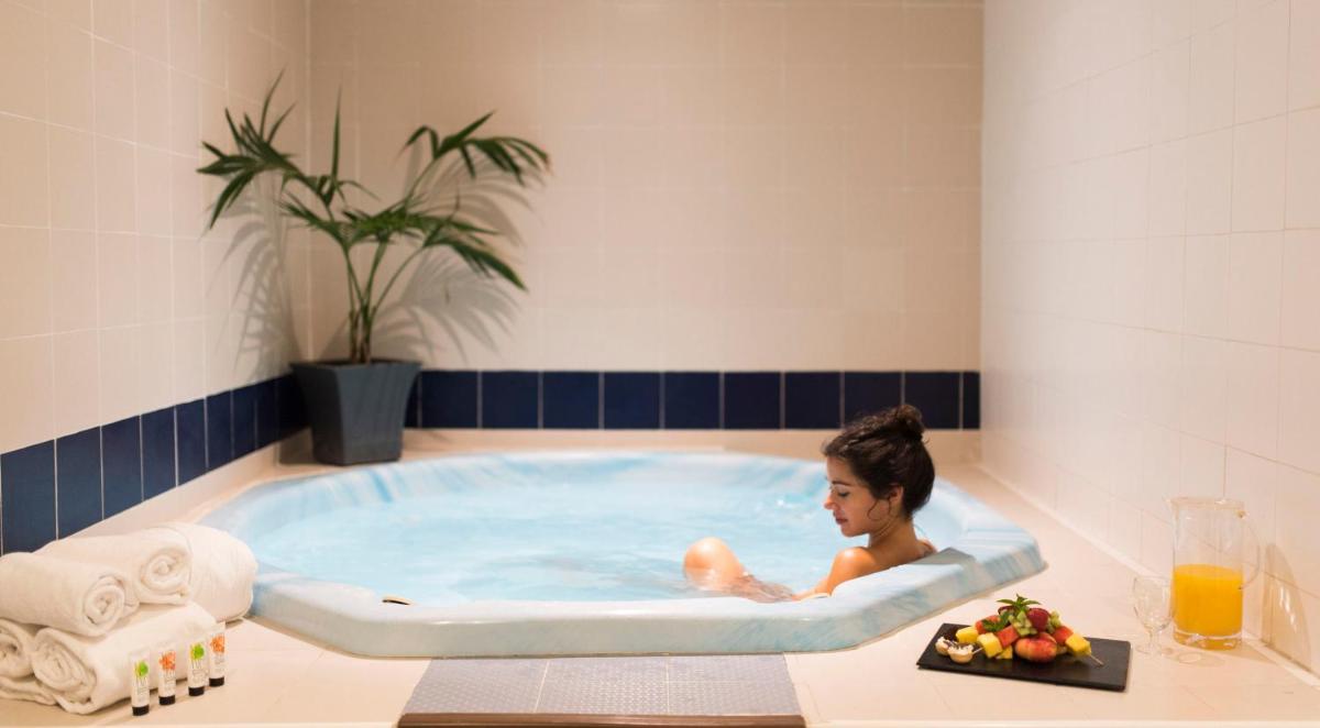 un hombre sentado en un jacuzzi en un baño en azuLine Hotel Bergantin, en Bahía de San Antonio