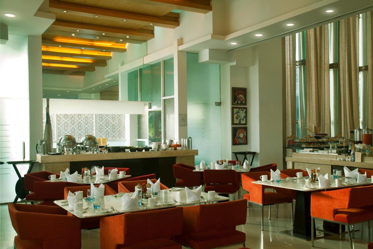 a dining room with tables and chairs and windows at Radisson Blu Hotel Pune Kharadi in Pune