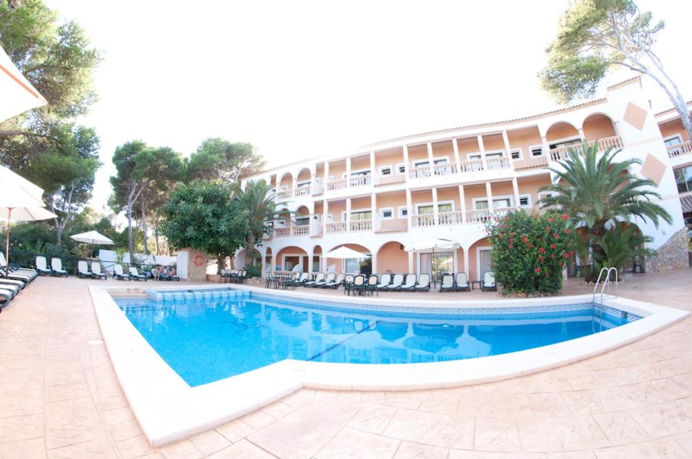 un hotel con piscina frente a un edificio en Hotel Cala Gat, en Cala Ratjada