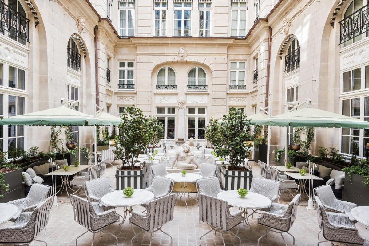 une cour avec des tables et des chaises et une fontaine dans l'établissement Hotel de Crillon, à Paris une cour avec des tables et des chaises et une fontaine dans l'établissement Hotel de Crillon, à Paris